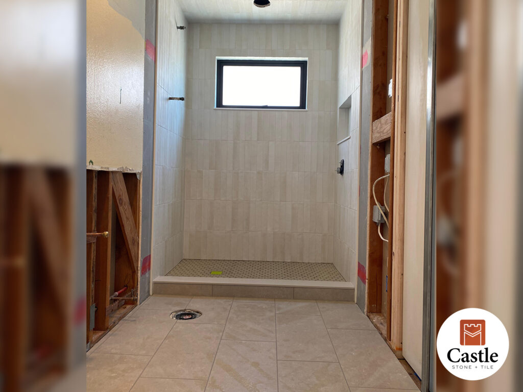This Carlsbad, CA bathroom features 3x11 stacked vertical tile on the walls and ceiling, paired with a 12x24 porcelain floor. The bold vertical lines and sleek finishes create a striking, modern space.